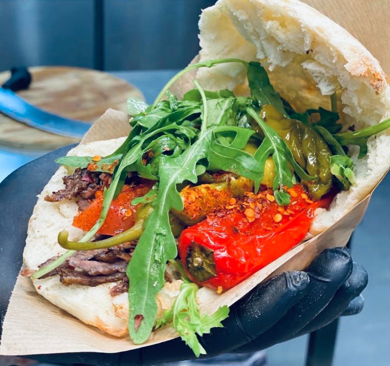 Döner mit Scheibenfleisch, gegrillter Paprika, Peperoni und Rucola im Fladenbrot